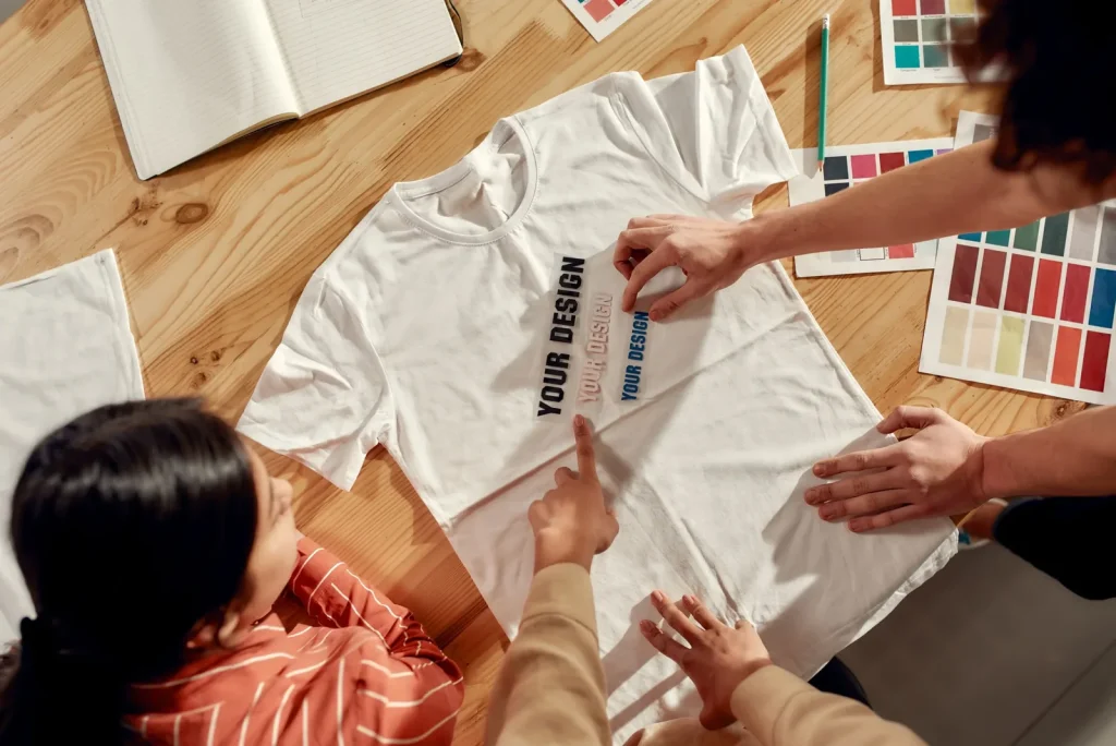 Een wit T-shirt met opdruk wordt bekeken op een werktafel